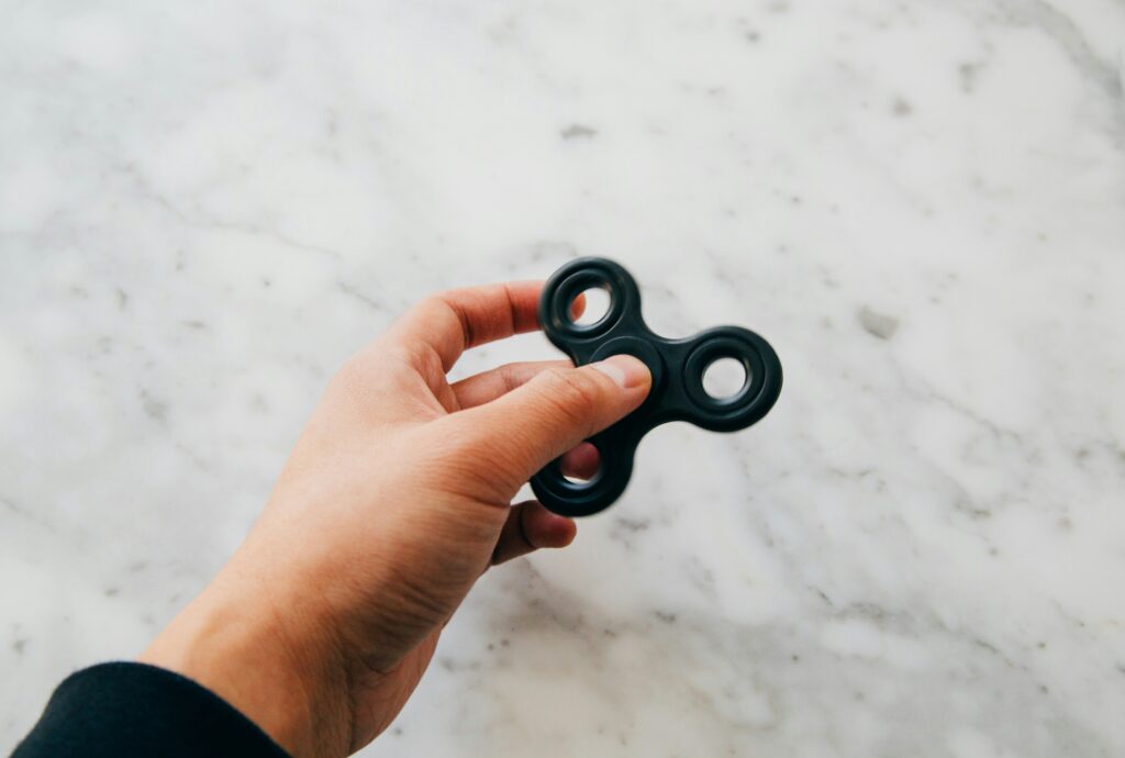 Black fidget spinner held by a client in a therapy session with a neurodivergent therapist in Stirling, used as a sensory tool to support autistic adults