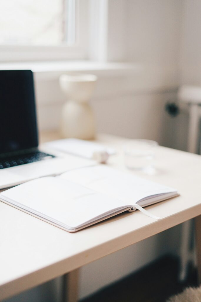 A photo representing online therapy. An image of a desk with a laptop and notebook.